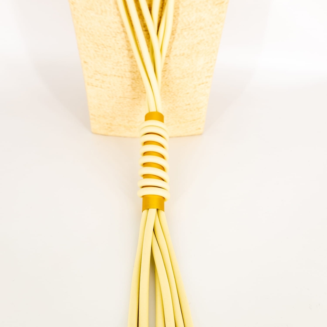 Nowoczesny naszyjnik Orsomarsoa – jasnobeżowy, długi, z frędzlami i metaliczną rurką.