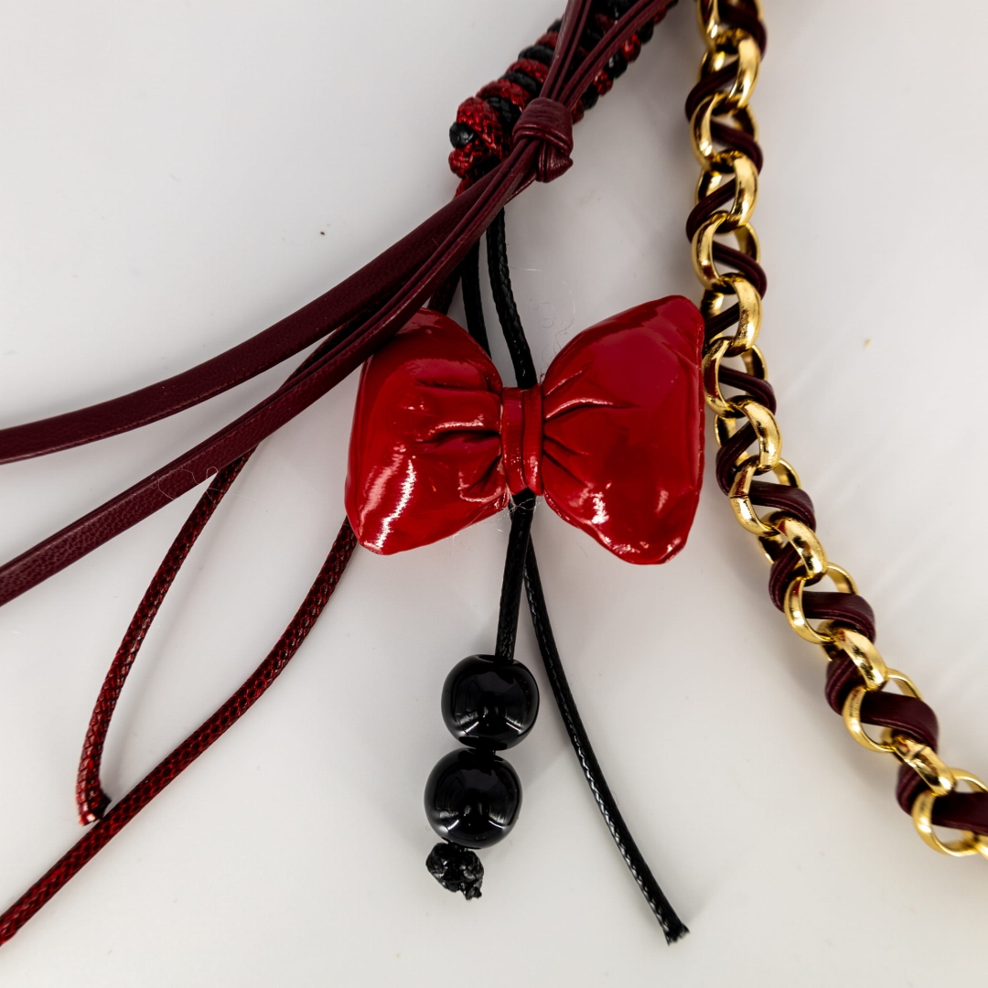 Bordowa przypinka dekoracyjna z kokardkami i złotymi okuciami.