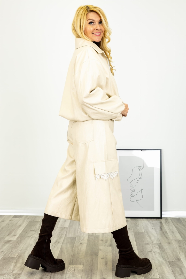 Beżowe spodnie culotte Landiona wykonane z gładkiej ekoskóry o szerokiej nogawce długości 7/8 z elastycznym pasem kieszeniami oraz imitacją kieszeni z koronką Antaresa