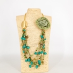 Naszyjnik z materiałowym kwiatem  Gragnano fasetowane połyskujące koraliki i marmurkowe kamienie i złote blaszki na łańcuszku o splocie typu ankier regulowany pistacjowy