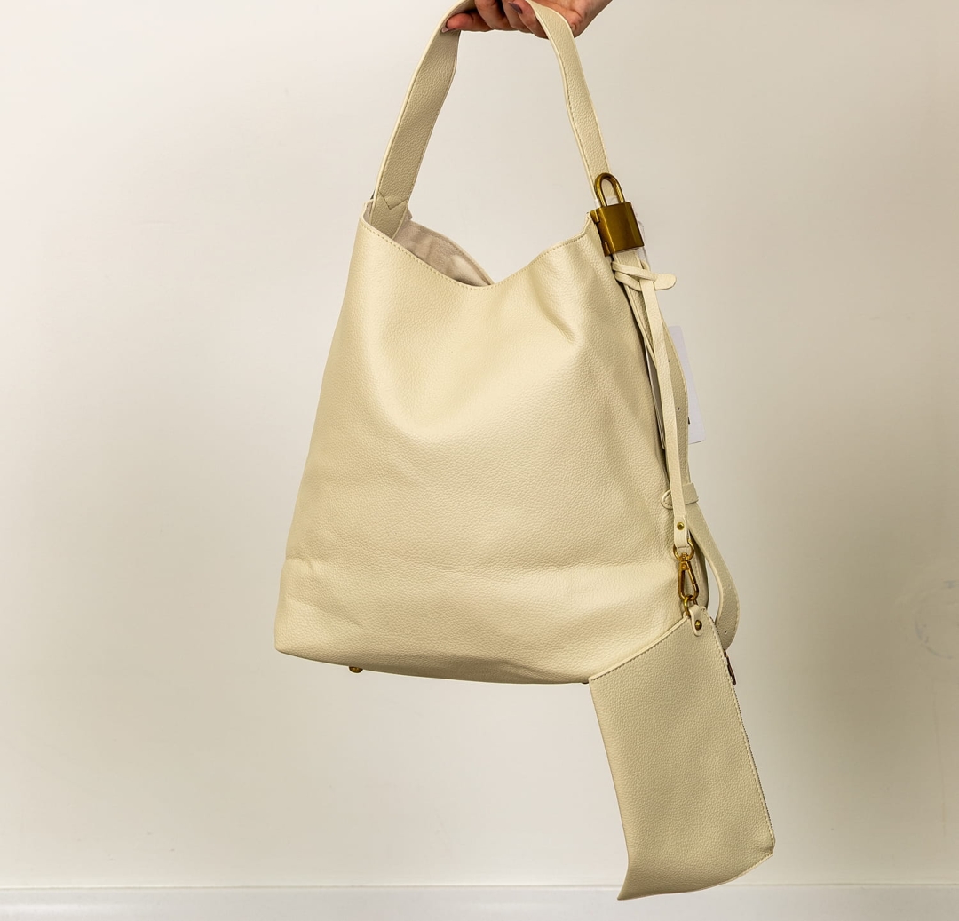 Beżowa torebka z ozdobną miedzianą kłódką i regulowanym uchwytem.