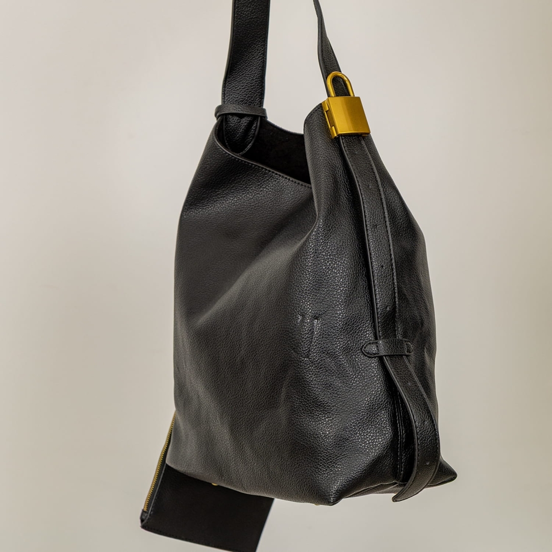 Czarna torebka z ozdobną miedzianą kłódką i regulowanym uchwytem.