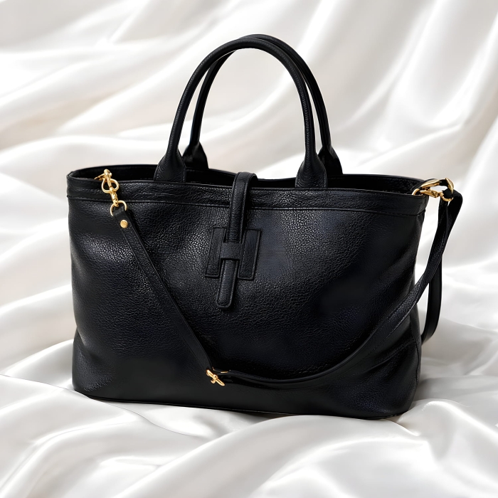 Czarna torebka damska skórzana z ozdobną tasiemką zabezpieczającą.