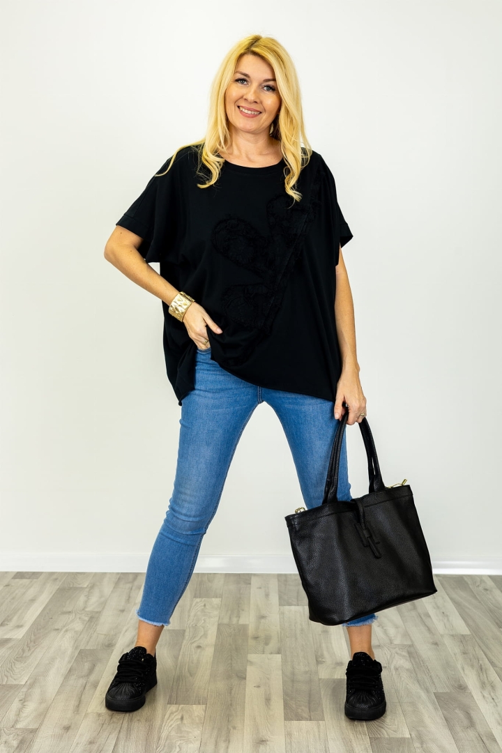 T-shirt bawełniany czarny Ingria z elementem asymetrii oraz ozdobą w postaci naszytego kwiatu na przodzie.