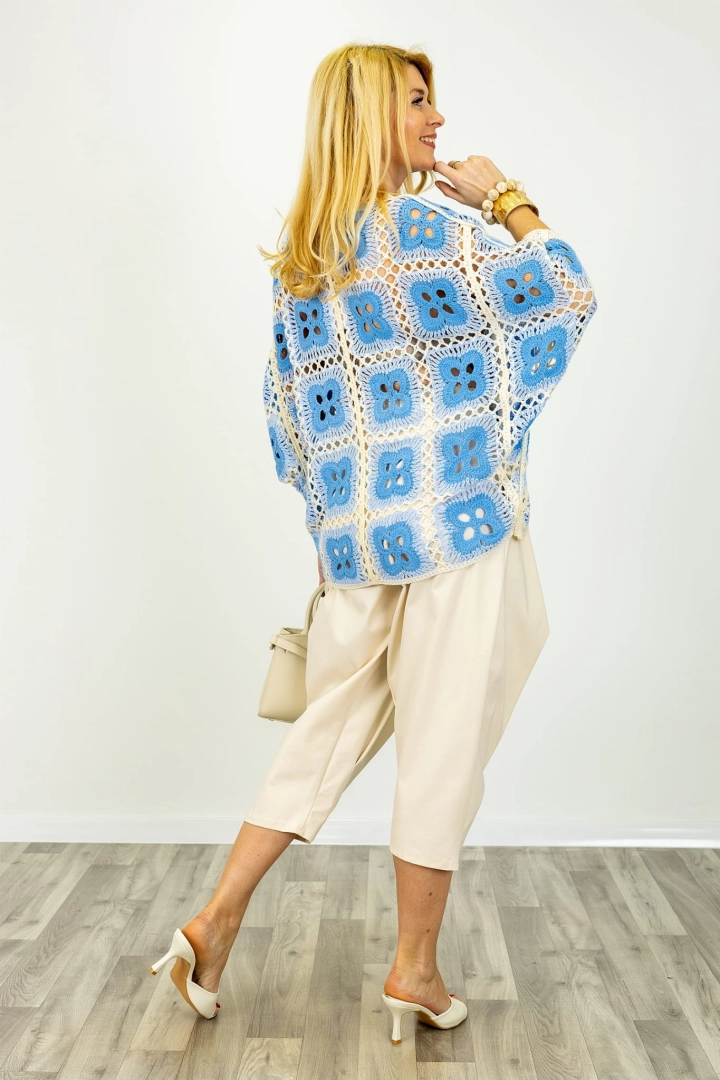 Tył narzutki oversize w beżowym kolorze, z ażurowym motywem kwiatów i rękawem kimono