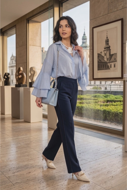 Koszula damska błękitna oversize w paski z falbankami przy rękawach tworzy lekką i elegancką stylizację.