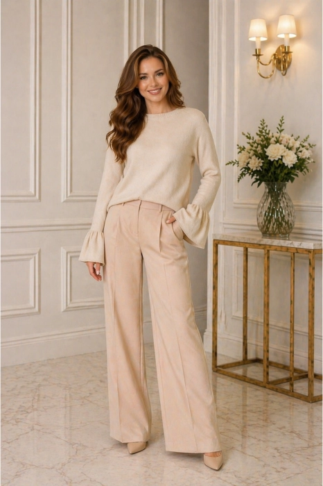 Sweter damski beżowy z okrągłym dekoltem i rękawami zakończonymi falbanką w codziennej stylizacji.